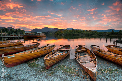 Fotografie Stunning sunset over wooden rowing boats on Derwentwater at Keswick in the Lake