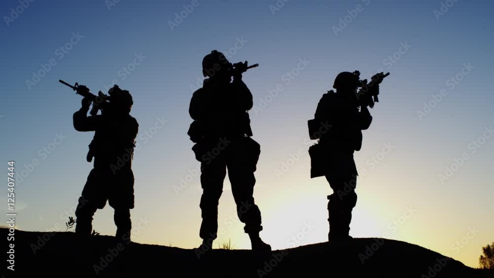 Squad of Three Fully Equipped and Armed Soldiers Standing on Hill in Desert Environment in Sunset Light. Slow Motion. Squad of Three Fully Equipped and Armed Soldiers Standing on Hill in Desert Environment in Sunset Light. Slow Motion.
