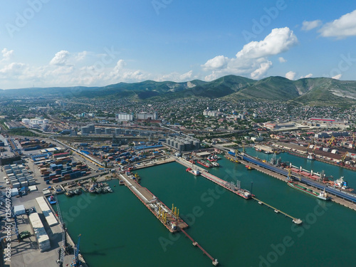 Industrial seaport  top view. Port cranes and cargo ships and barges. Loading and shipment of cargo at the port. View of the sea cargo port with a bird s eye view