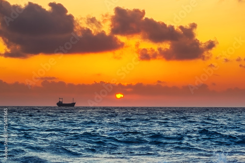 Seascape with cargo ship in sunset time