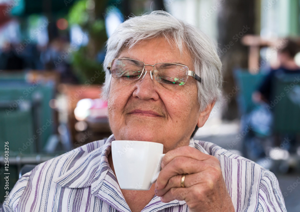 Elderly woman with cup of coffee at summer cafe Elderly woman with cup of coffee at summer cafe