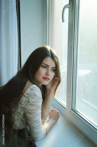 beautiful girl with long brown hair looking in the window