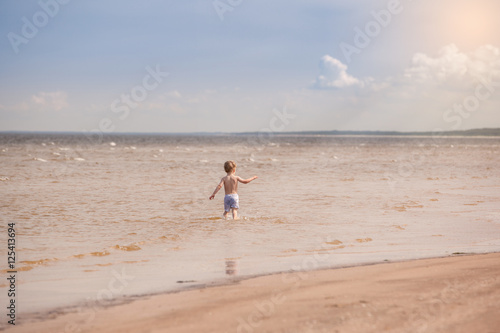 Children run along the beach and splatters with water