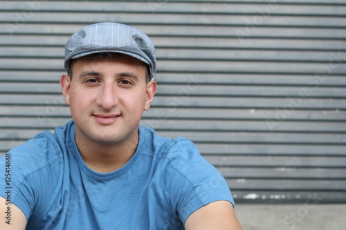 Portrait of handsome real looking man in hat sitting outdoors 