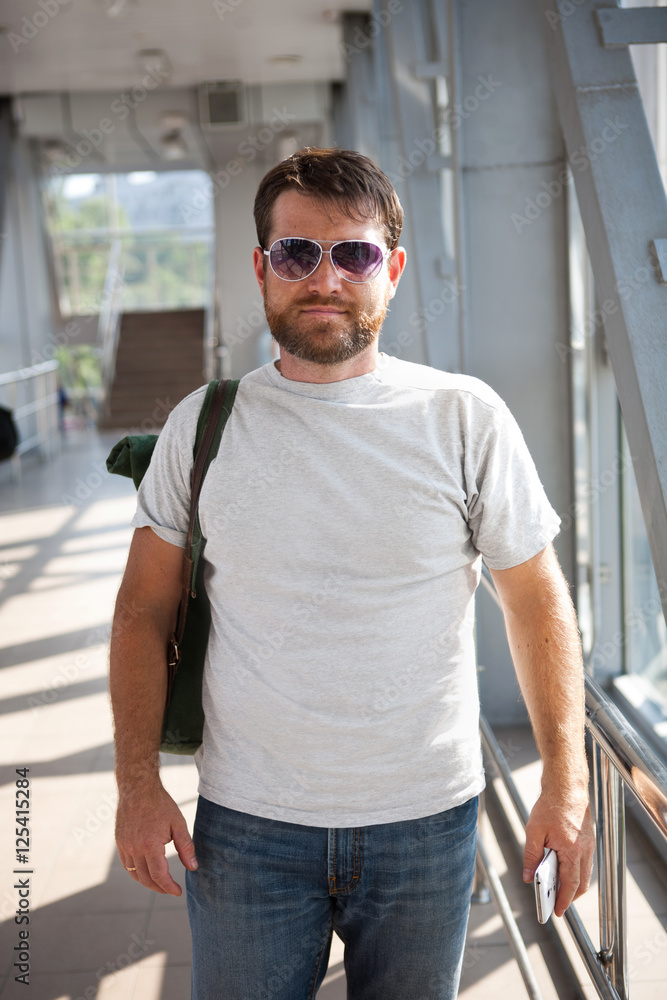 bearded man in sunglasses standing with phone in his hand bearded man in sunglasses standing with phone in his hand