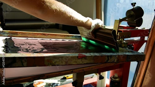 Traditional silk-screen printing - operator moves the fill bar to push the ink through the holes in the mesh photo