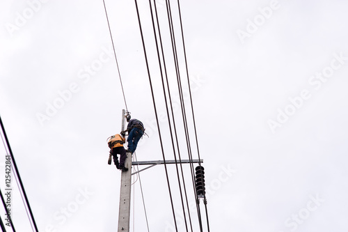 Electrician lineman repairman worker at climbing work on electric post power pole