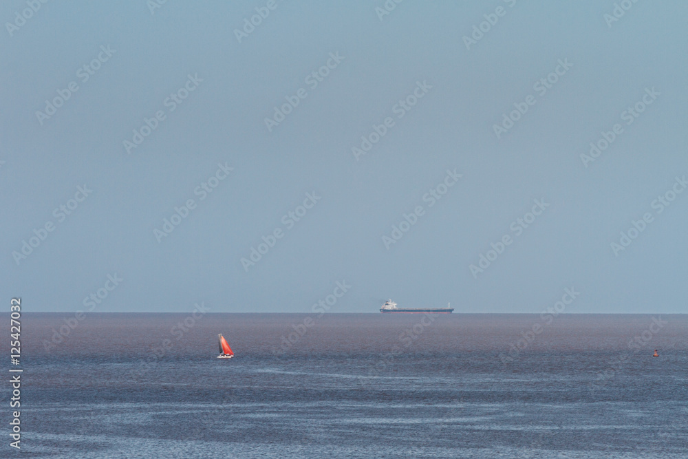Sailboat in the Rio dela Plata with a cargo ship on the horizon