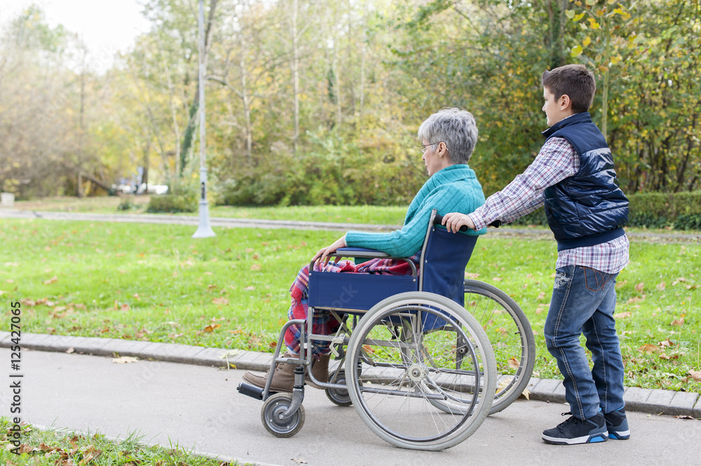 Grandson is pushing his grandmother in a wheelchair