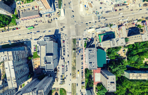 Aerial city view with crossroads and roads, houses, buildings, parks and parking lots, bridges. Urban landscape. Copter shot. Panoramic image.