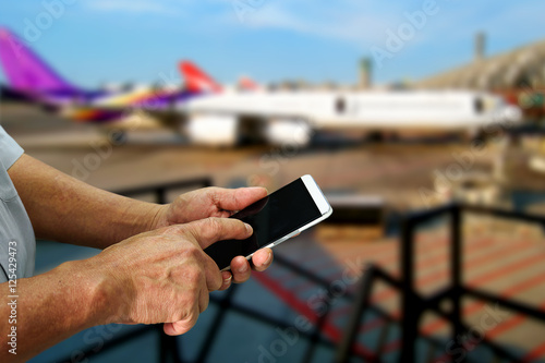 High tech old man hands use smartphone , elder lifestyle and online check in concept with airplane background , copyspace area