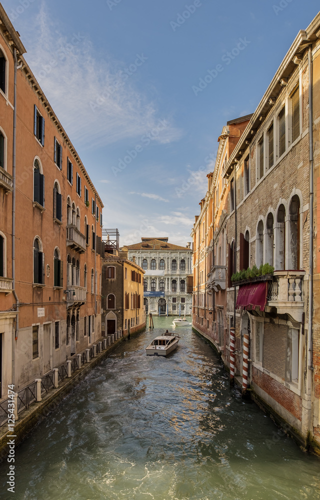 Venice cityscape at early morning. Narrow canal among old colorful brick houses in Venice, Italy.