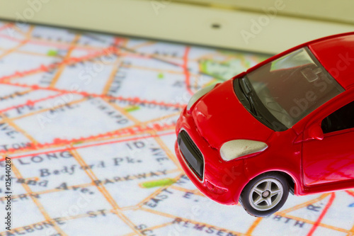 horizontal photo of closeup red car toy on the map in tablet screen