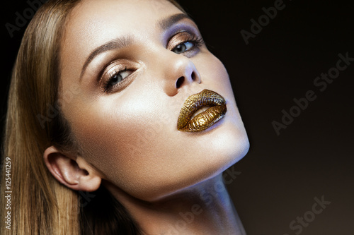 Fotografie Beautyful girl with gold glitter on her face and body