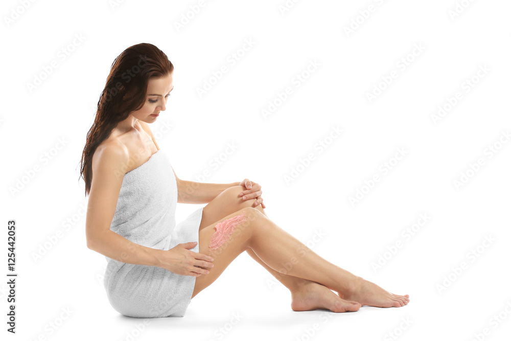 Young woman applying nourishing scrub on leg and sitting on white background Young woman applying nourishing scrub on leg and sitting on white background