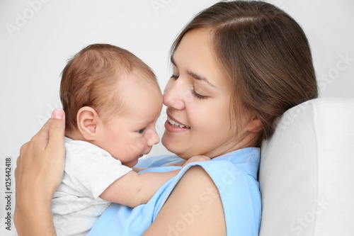 Portrait of young woman holding her baby, close up view