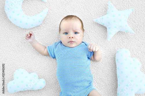 Cute baby lying on bedsprea...