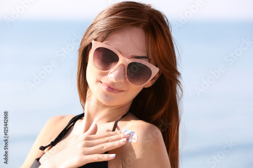 Young woman using sunscreen on the sea background