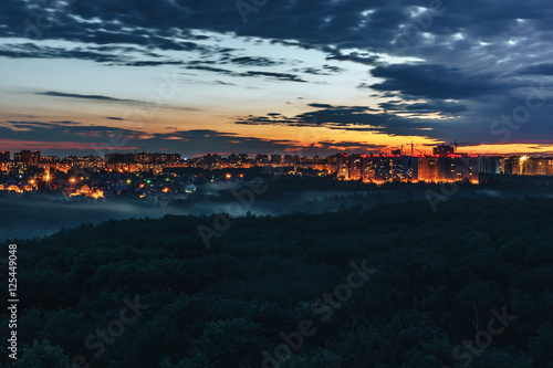 Colorful sunset, clouds, city, forest park in the foreground