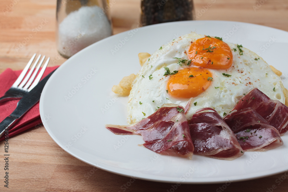Appetizing Spanish Iberian cured ham with fried egg and chips on Appetizing Spanish Iberian cured ham with fried egg and chips on