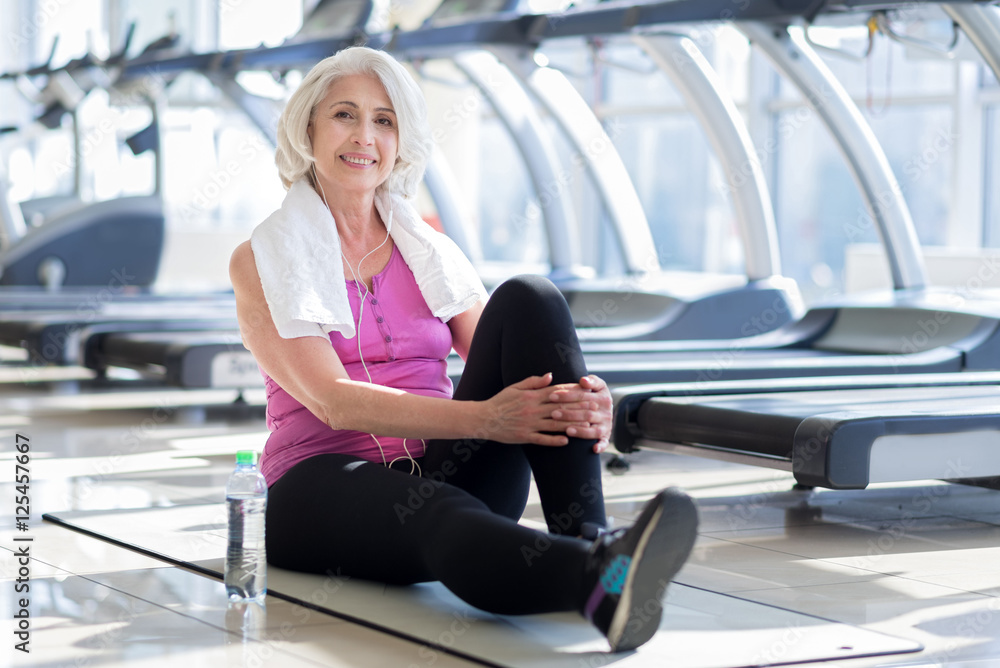 Pretty smiling senior woman sitting in a gym Pretty smiling senior woman sitting in a gym