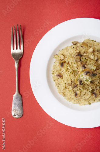 A dinner bowl of chicken and mushroom risotto rice on a bright red background
