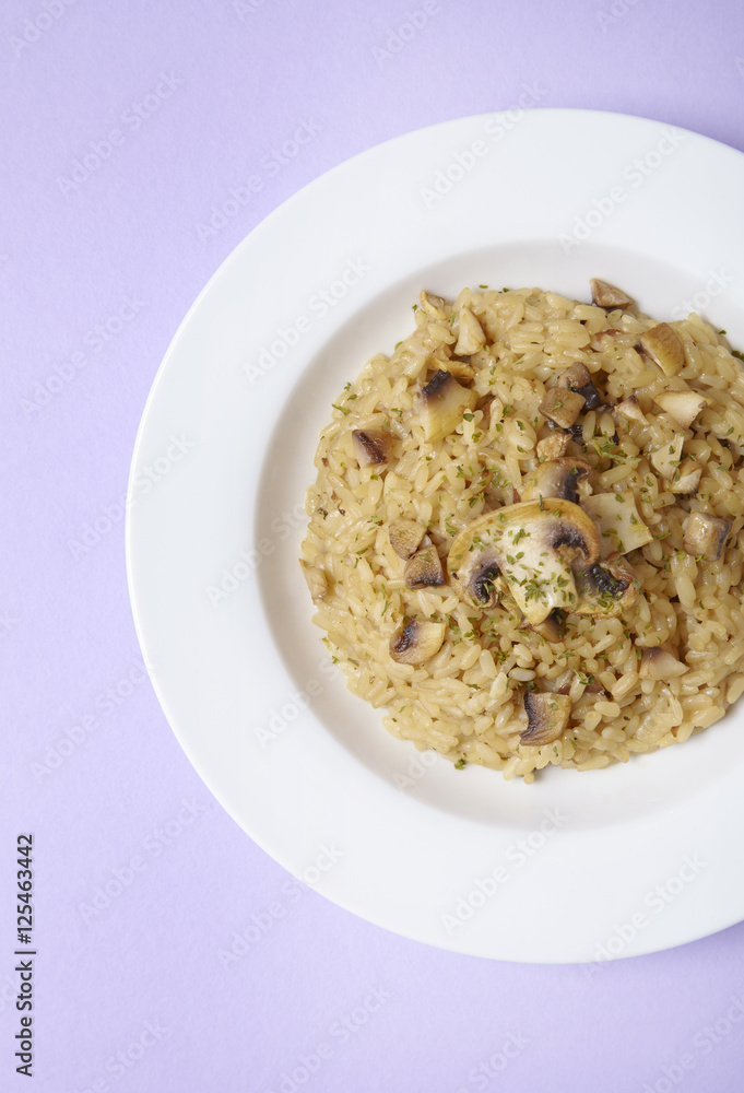 A dinner dish of chicken and mushroom risotto on a pastel purple colored background