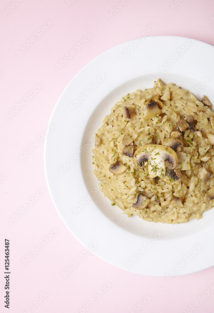 A dish of chicken and mushroom risotto on a pastel pink background A dish of chicken and mushroom risotto on a pastel pink background