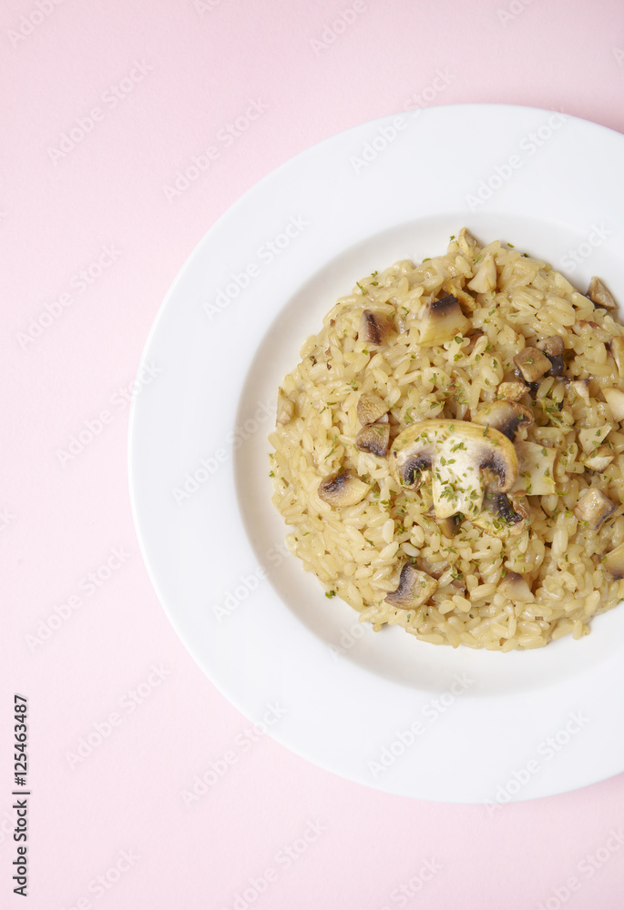 A dish of chicken and mushroom risotto on a pastel pink background