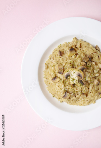 A dish of chicken and mushroom risotto on a pastel pink background