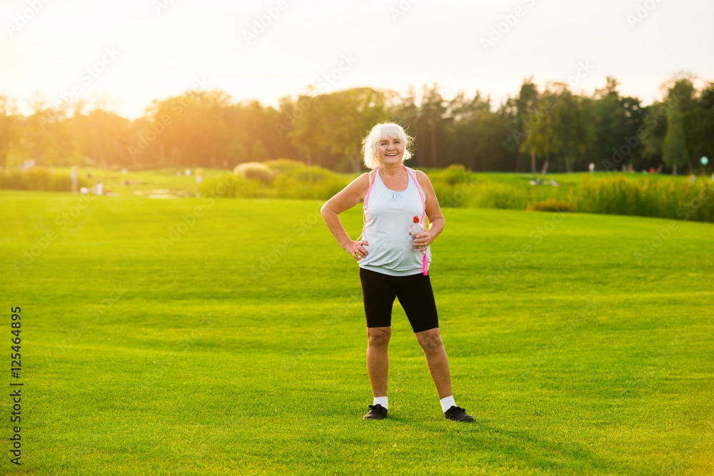 Senior woman with water bottle. Lady is standing on grass. Aerobic workouts improve health. All you need is motivation. Senior woman with water bottle. Lady is standing on grass. Aerobic workouts improve health. All you need is motivation.