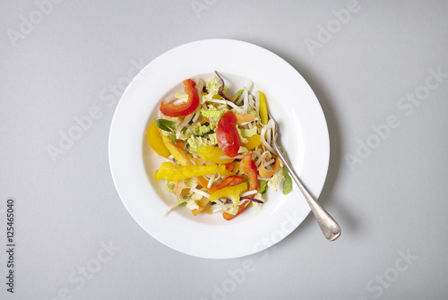 Aerial view of a bowl of fresh, chopped stir fry vegetables on a soft grey background