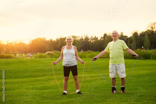 Couple with skipping ropes. Senior people on meadow. Test your endurance. Aerobic trainings for pensioners.
