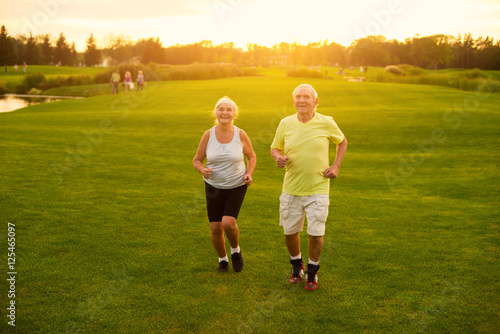 Couple jogging on grass. Senior man and woman smiling. Active leisure of pensioners. Save your health.