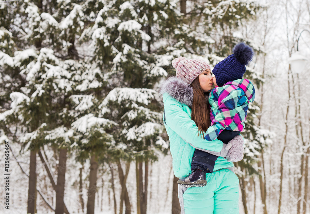 Mother and little toddler girl walking in the winter forest and having fun with snow. Family enjoying winter. Christmas and lifestyle concept. Mother and little toddler girl walking in the winter forest and having fun with snow. Family enjoying winter. Christmas and lifestyle concept.