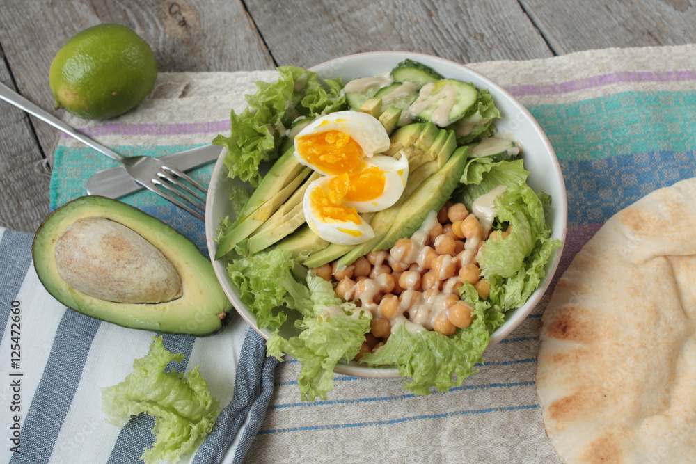 healthy salad in a bowl. avocado, chickpeas, cucumber and egg. more greens every day