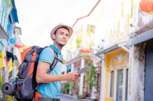 Tourism and technology. Concept of online map. Traveling backpacker young man using digital tablet  outdoor. photo