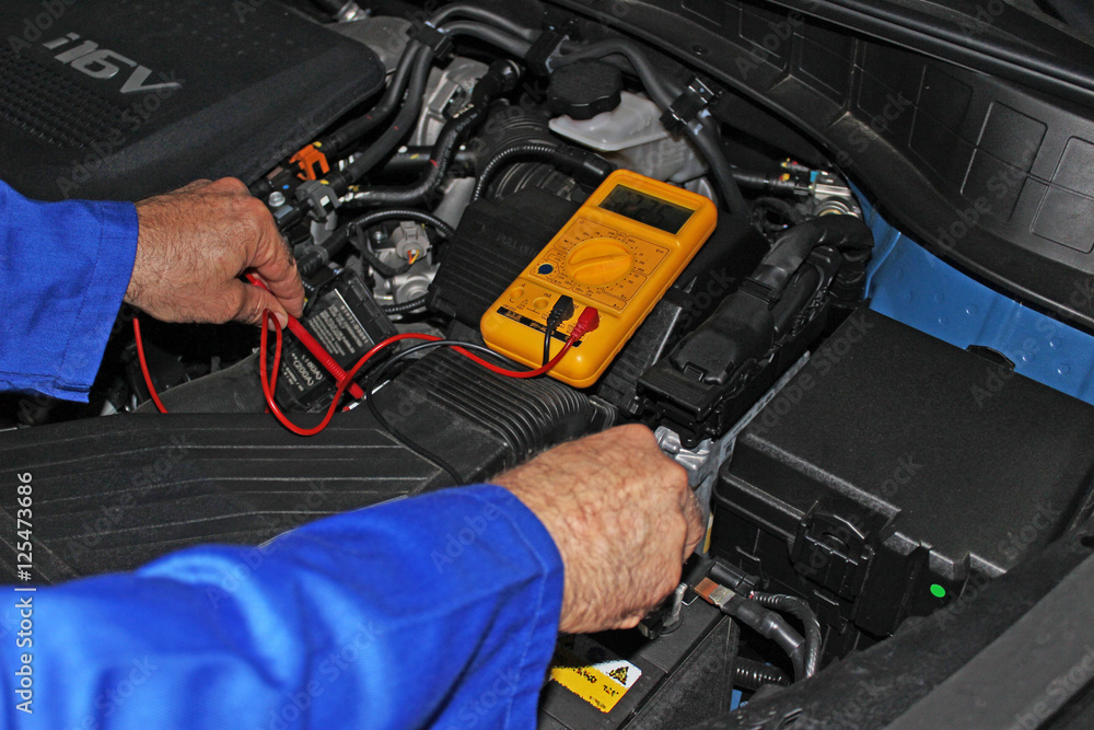 Mecánico comprobando la bateria del coche Mecánico comprobando la bateria del coche