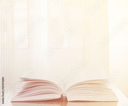 Open book on wood background with sunlight