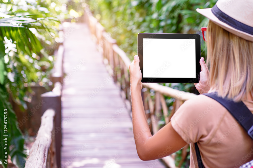 Travelling concept. Technology and adventure. Young woman using tablet computer in jungle.