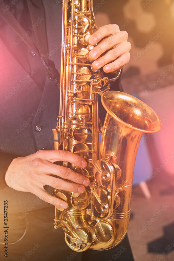 Obraz premium Young man in a suit hold a saxophone musical instrument