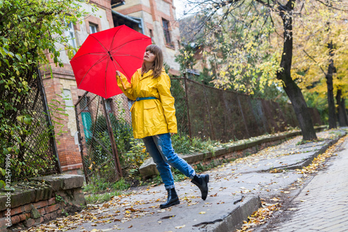 Enjoying autumn days. Woman in yellow raincoat walking down the street