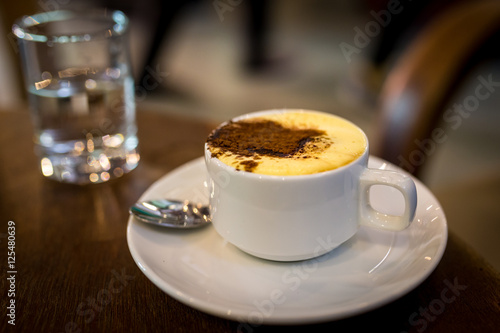 Cup of vietnamese egg coffee and a glass of water on a wooden table in Hoi An, Vietnam 