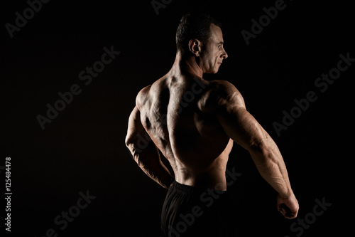 torso of attractive male body builder on black background. © master1305