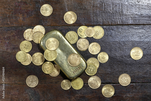 Goldbarren mit verschiedenen europ  ischen Goldm  nzen aus dem 19. 20. Jahrhundert auf rustikalem Holztisch
