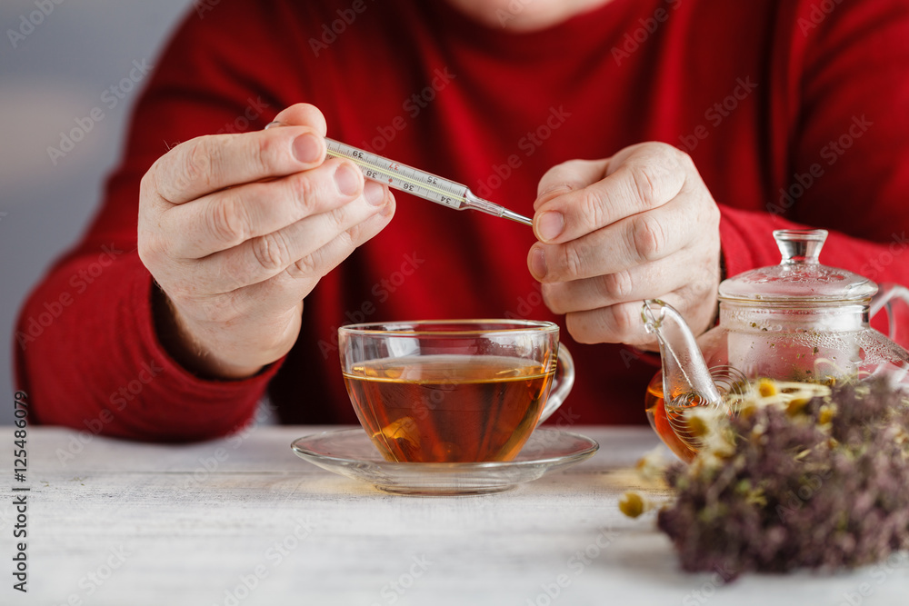 Man Cold / Ill man with scarf and tea cup, sneezing into handker Man Cold / Ill man with scarf and tea cup, sneezing into handker