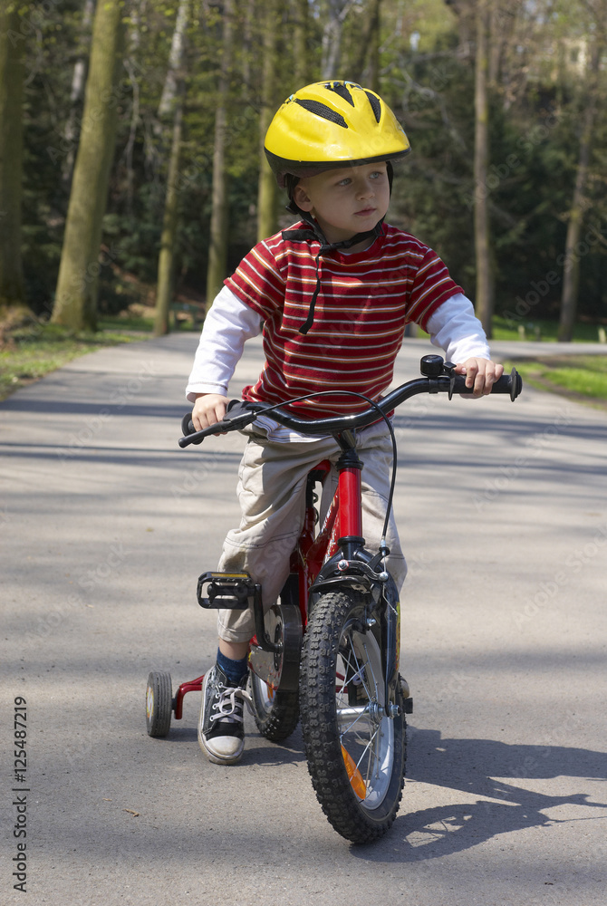 Young boy riding his first bicycle with training wheels Young boy riding his first bicycle with training wheels