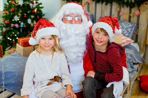 Santa Claus and two children sitting on the bed