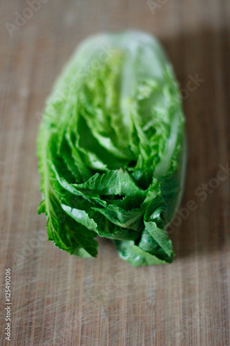 Fresh Romaine lettuce hearts on a bamboo cutting board with a dark background