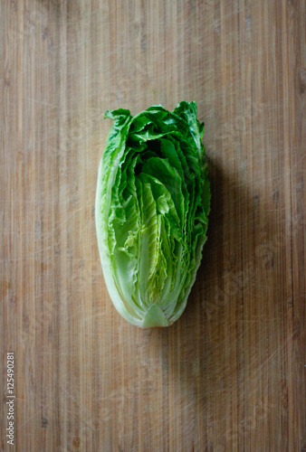 Fresh Romaine lettuce hearts on a bamboo cutting board with a dark background